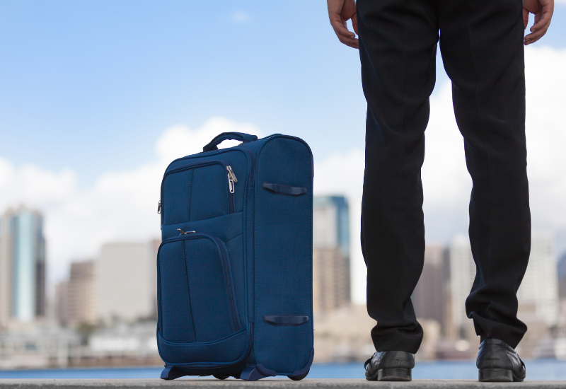 Traveler standing next to a suitcase on a street- annual travel insurance