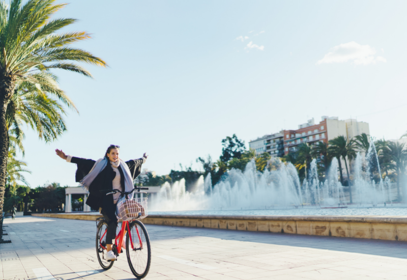 Carefree traveler with arms high riding a bicycle in Valencia, Spain