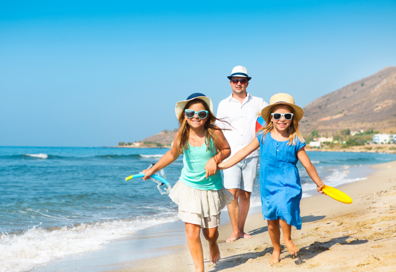 Best family travel insurance- family running on sunny beach