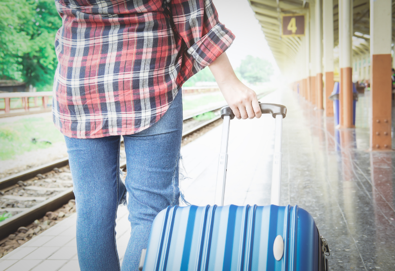 Young traveler pulling a suitcase at a railroad station